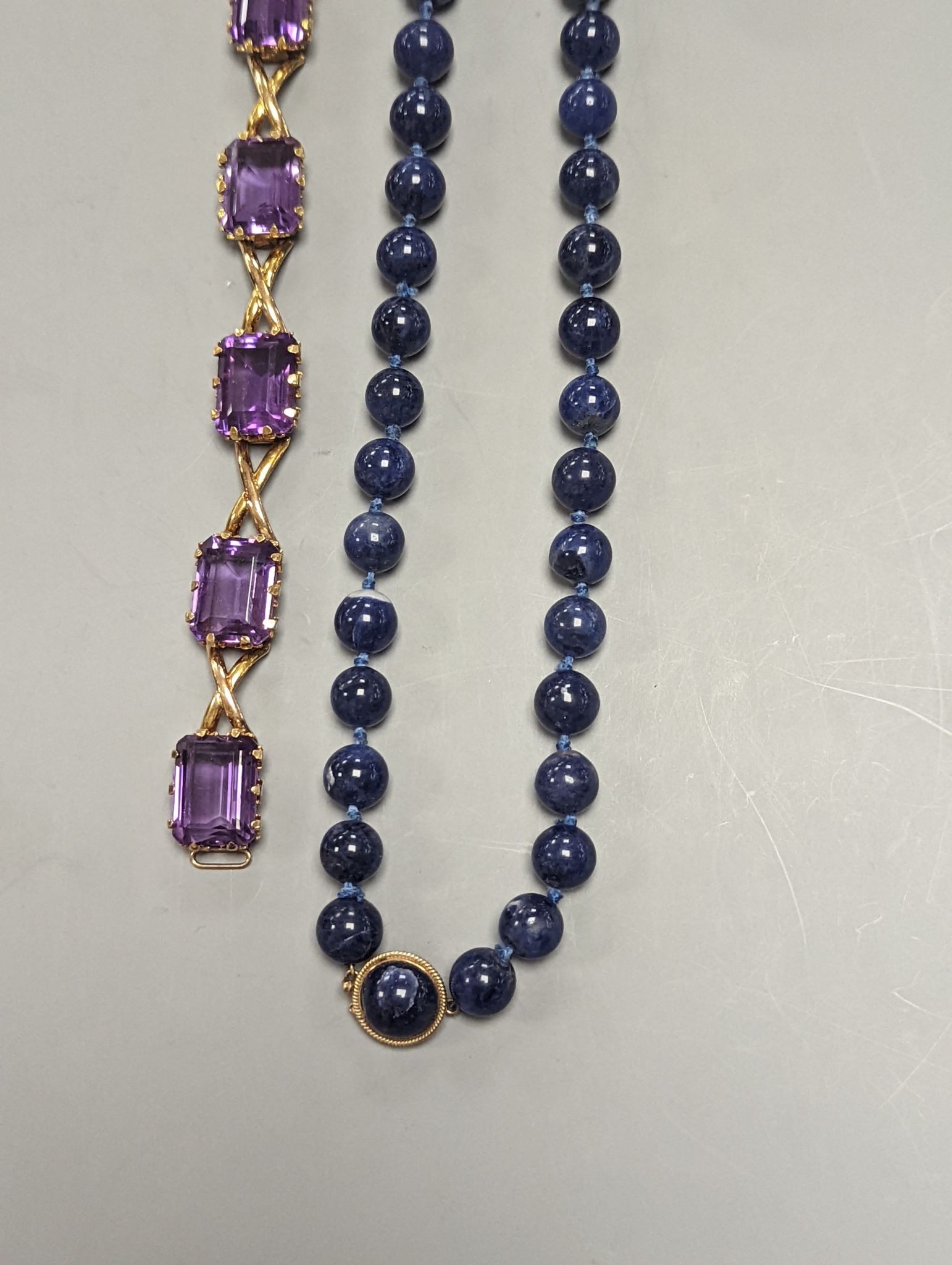 A yellow metal and six stone emerald cut amethyst set part bracelet(a.f.), 17.1cm and a modern single strand lapis lazuli bead necklace with 14k yellow metal clasp.